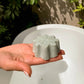 Jabon facial de espirulina Florina en una mano, delante de una bañera